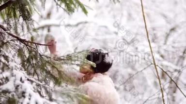 一个甜美的女孩从冬天的树枝上摇雪。 <strong>冬季运动会</strong>，节日快乐，圣诞节假期.. 粉色